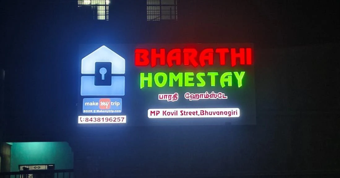 Illuminated Bharathi Homestay sign with its name in English and Tamil
